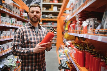 A man holds a fire extinguisher in his hand. A buyer in a hardware store selects a product