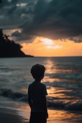 Fototapeta premium silhouette of boy standing at sunset by the sea