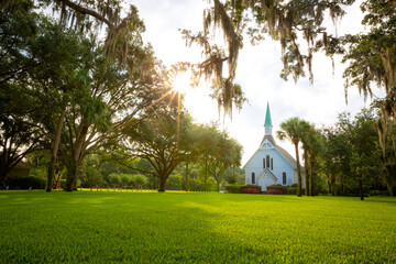 White episcopal church with grassy yard surrounded by trees