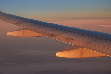 Obraz premium Flying on a plane, rising sun hitting wing