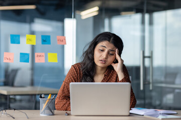 Upset and sad woman reading email, businesswoman looking at laptop screen with hand on head,...