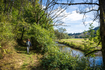 Fototapeta premium Frau mit Rucksack beim Wandern am Fluss