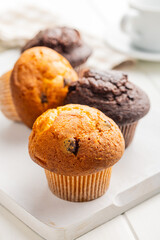 Sweet muffin cakes on cutting board on white table.