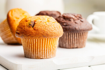 Sweet muffin cakes on cutting board on white table.