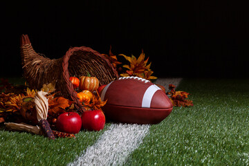 A cornucopia with a football on a grass field with stripe and dark background