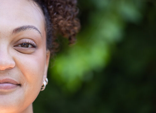 Smiling woman with curly hair with curly hair outdoor, close-up portrait, copy space