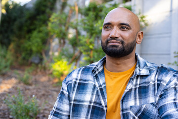 Smiling man in plaid shirt enjoying outdoor time in home garden