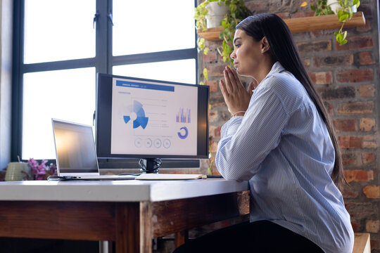 Analyzing data on computer, woman working in modern office environment