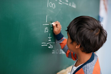 Little boy, writing and mathematics with chalkboard for equation, education or learning at school....