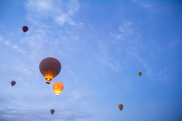 Hot air balloons glowing at dawn over Cappadocia's serene sky, creating a magical contrast with the soft morning clouds.