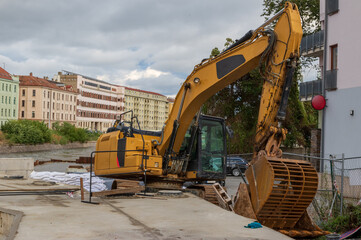 Yellow excavator on the bank of the river Svratka, Brno, Czech republic, floods after storm Boris,...