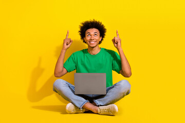 Full length photo of cheerful positive guy dressed green t-shirt writing modern device showing up emtpy space isolated yellow color background