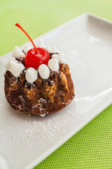 Mini bundt cake with cherry topping on white plate