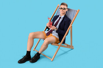 Funny businessman with cocktail sitting in deck chair on blue background