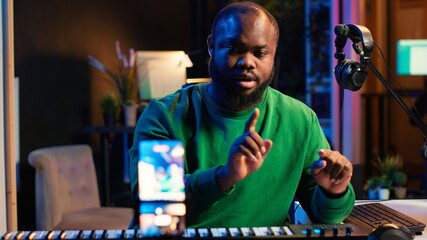 Musician doing online paid classes to help people play piano notes, teaching lessons from his home studio and recording video tutorials. Musical instructor playing midi controller keyboard. Camera A.