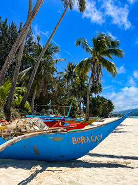 A fishing boat with Boracay sign on the beach with palm trees in the background