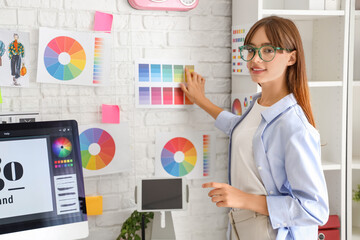 Female graphic designer with color palettes on wall in office