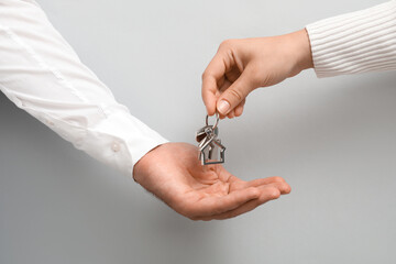 Couple with keys from their new house on light background, closeup