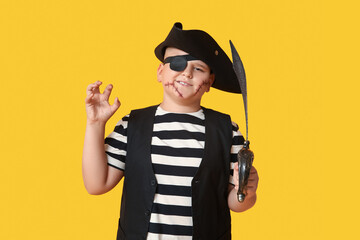 Cute happy boy with sword dressed as pirate for Halloween party on yellow background