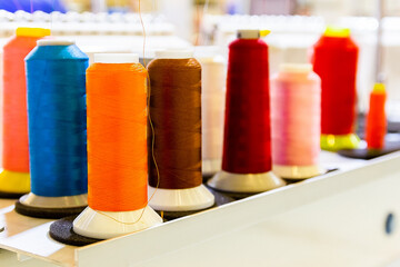 Spools of colored thread on an industrial sewing machine