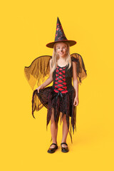 Cute happy girl dressed as witch for Halloween party on yellow background