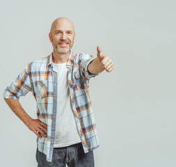 A man with a plaid shirt and white shirt is giving a thumbs up. He is smiling and he is happy