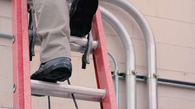 Person coming down an extension ladder wearing boots