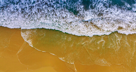 Blue ocean wave on yellow sandy beach. Sea waves and sand the summer background. Summer seascape beautiful waves, blue sea water. Top view from drone. Sea aerial view, tropical nature background.