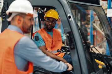 African american male forklift operator engages with colleague in a warehouse.