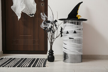 Vase with tree branches and bin in hallway decorated for Halloween