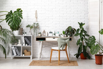 Interior of office with workplace, shelf unit and green plants