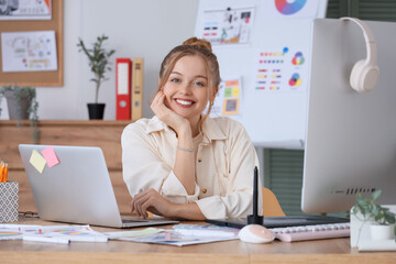 Female web designer working with laptop at table in office