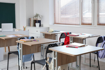 Interior of empty classroom with school desks and greenboard