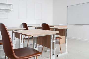 Interior of empty classroom with school desks and clean whiteboard