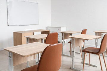 Interior of empty classroom with school desks and clean whiteboard