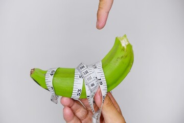 banana wrapped around a centimeter measuring device on a white background