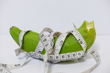  banana wrapped around a centimeter measuring device on a white background