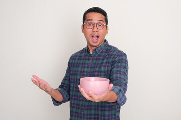 A man showing wow face while holding empty dinning bowl