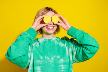 Photo of shiny attractive lady dressed tie dye sweatshirt holding lemons cover eyes empty space isolated yellow color background