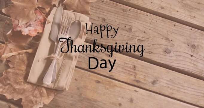 Animation of happy thanksgiving day text over cutlery on wooden background