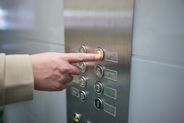 unrecognizable woman presses a button on a elevator button panel display with Braille instructions to assist people with visual impairments
