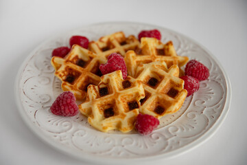 Waffles with raspberries on a white plate. Selective focus.