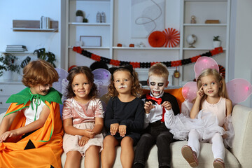 Funny children wearing costumes for Halloween celebration in room