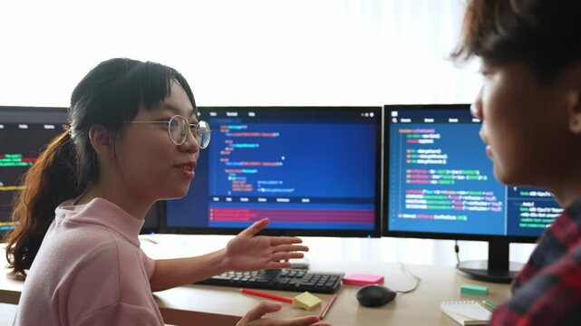 Slow motion back end software developer engineer for computer programming working together on debugging writing computing code, solving complex algorithms display on monitor in office. Burgeoning