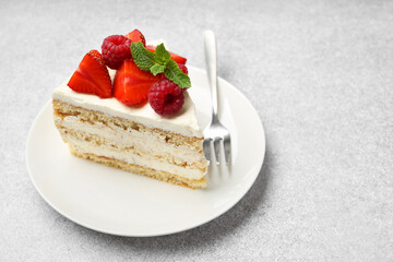 Piece of tasty sponge cake with fresh berries and mint served on light gray table, space for text