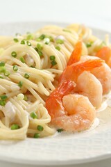 Delicious pasta with shrimps and green onions on plate, closeup