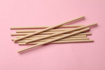 Bamboo drinking straws on pink background, top view