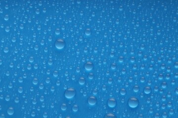 Water drops on blue background, top view