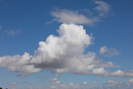 Cloudscape photograph of white and grayish fluffy clouds also swirly random clouds covering blue sky.