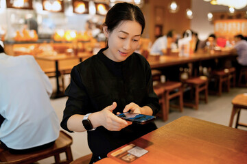 Young Woman Engaging with Mobile Technology in a Cozy Restaurant Setting